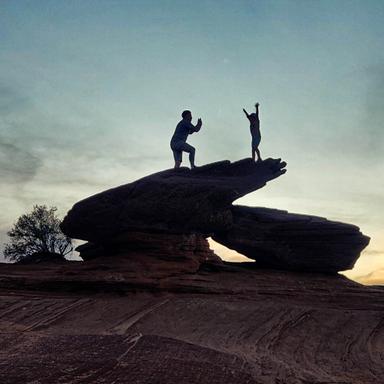 Parent taking photo of child on a rock